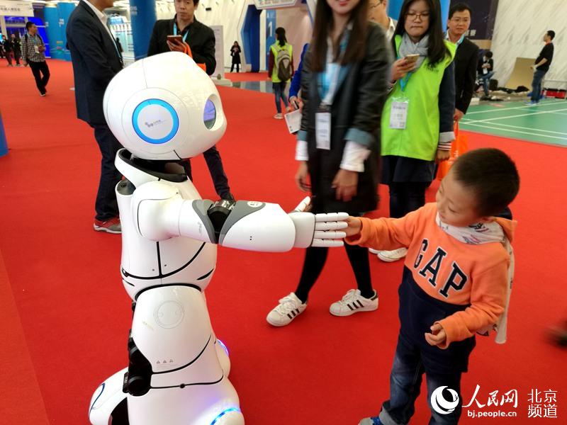 小朋友与机器人握手互动。人民网 孟竹 摄