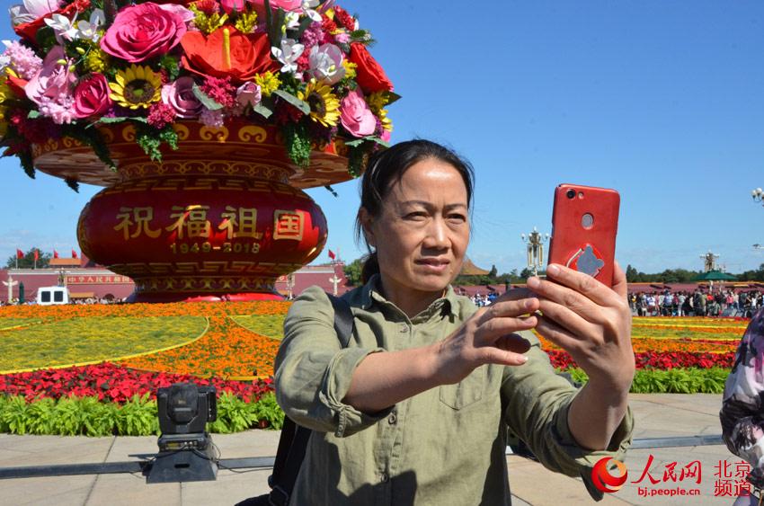 游人在“祝福祖国”大花篮前自拍。人民网尹星云 摄