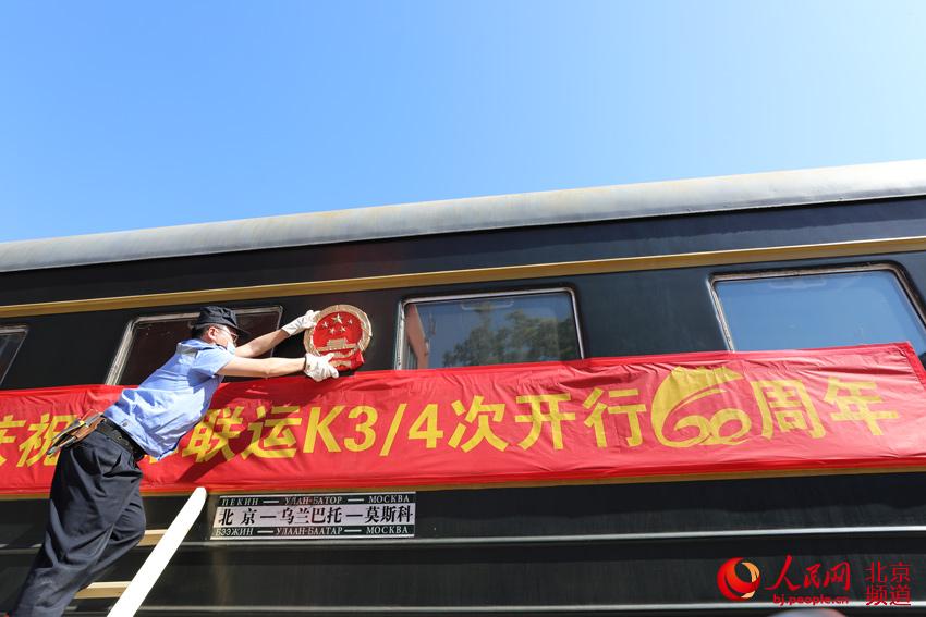 工作人员为K3/4次国际联运列车挂上国徽。人民网尹星云 摄