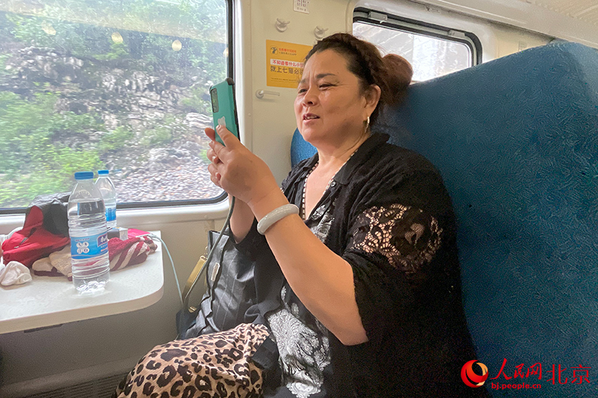 登上列车的群众用手机向家人报平安。人民网记者 尹星云摄