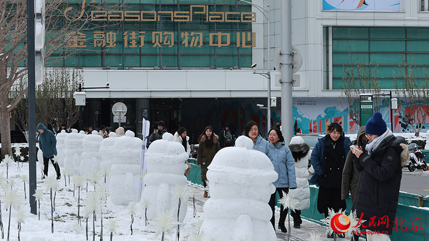 行人路过金融街街心花园的雪人