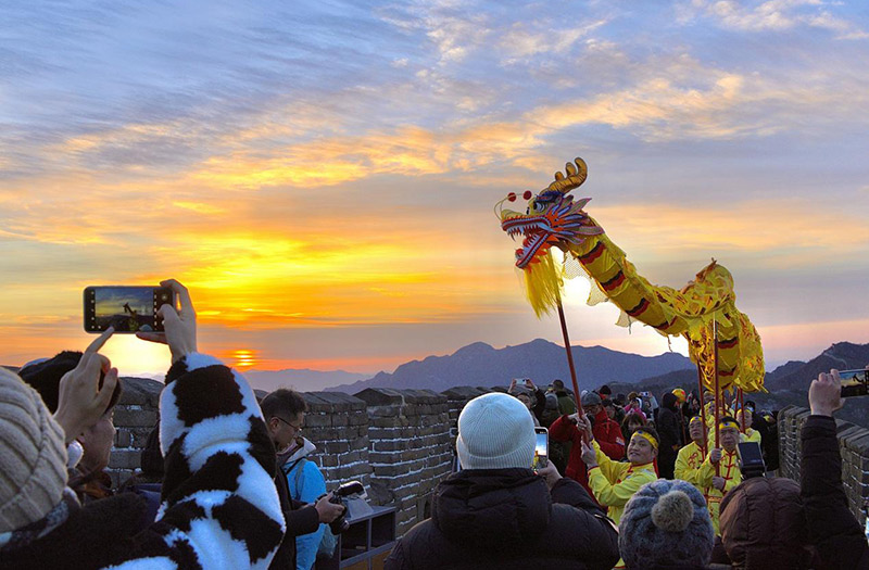 2025年1月1日，游客在北京慕田峪长城景区观看新年日出。活动现场还有精彩的舞龙舞狮表演。