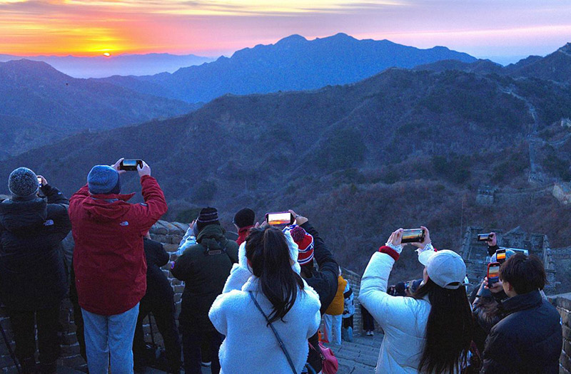 2025年1月1日，游客在北京慕田峪长城景区观看新年日出。活动现场还有精彩的舞龙舞狮表演。