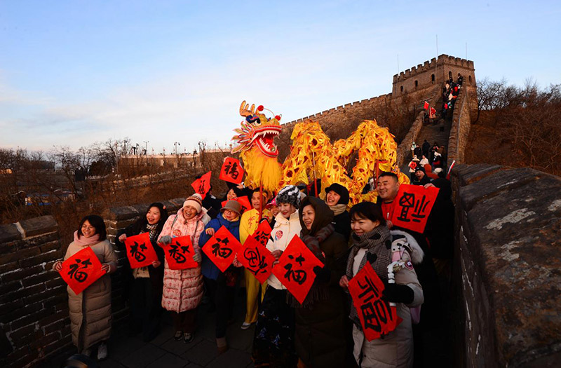 2025年1月1日，游客在北京慕田峪长城景区观看新年日出。活动现场还有精彩的舞龙舞狮表演。