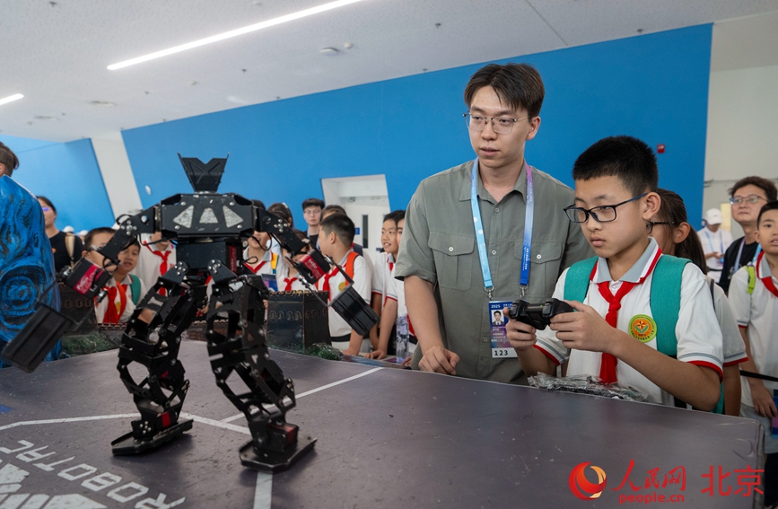 小朋友正在操控人形机器人体验功夫搏击。人民网记者 翁奇羽摄